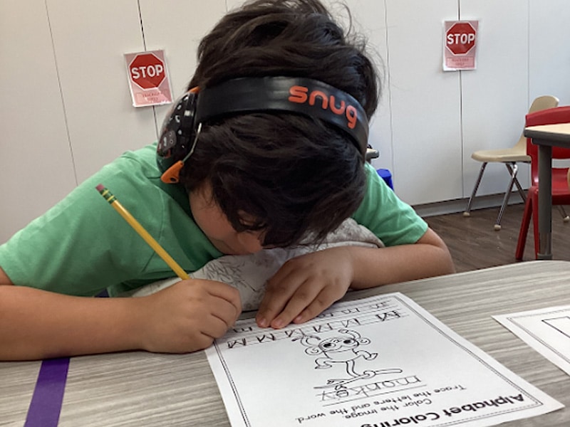 child practicing writing the letter m at Merlin Day Academy