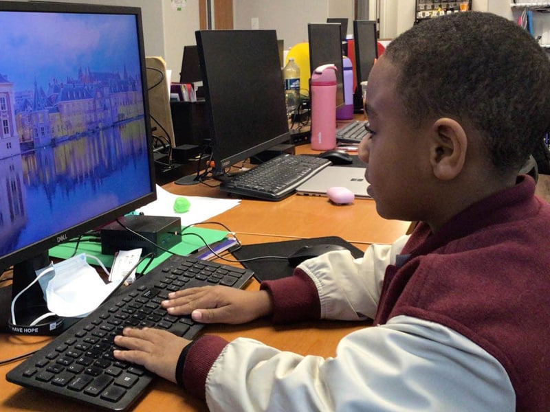 child typing on computer keyboard