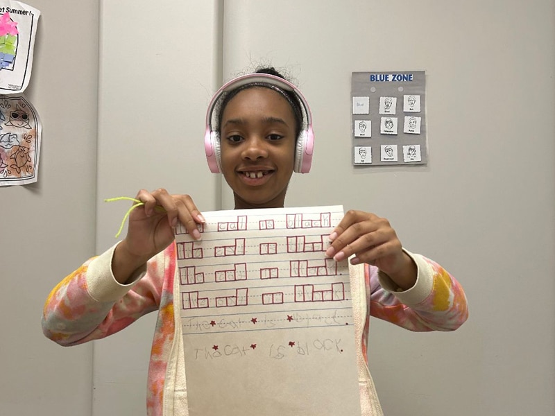 child holding up worksheet smiling